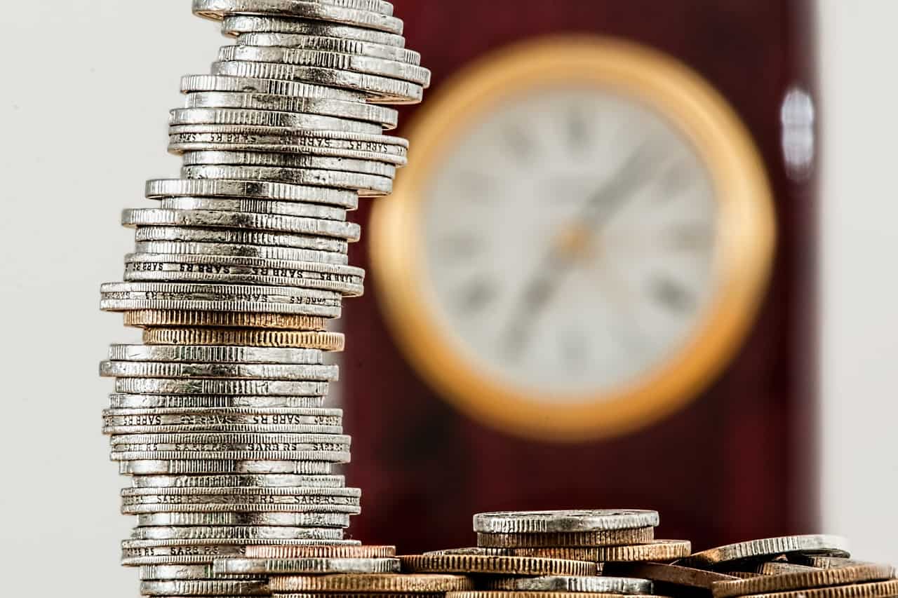 Stack of Coins and Clock Behind