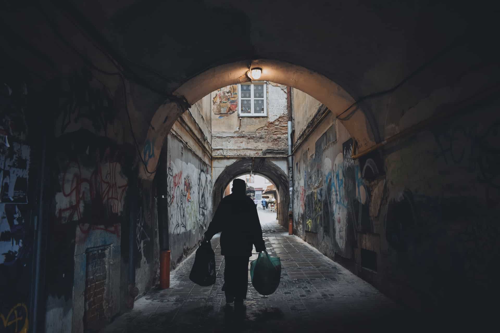 Person Carrying Bag in an Alley Person Carrying Bag in an Alley