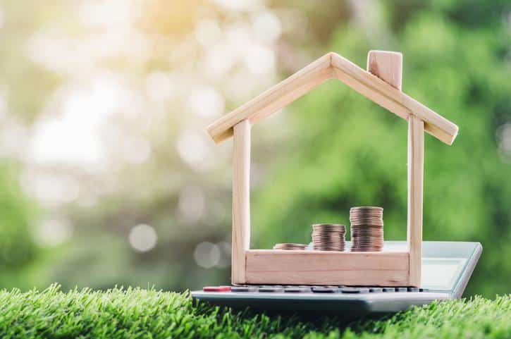 Coins placed is a staircase in a House is on the calculator placed on the grass. planning savings money of coins to buy a home.