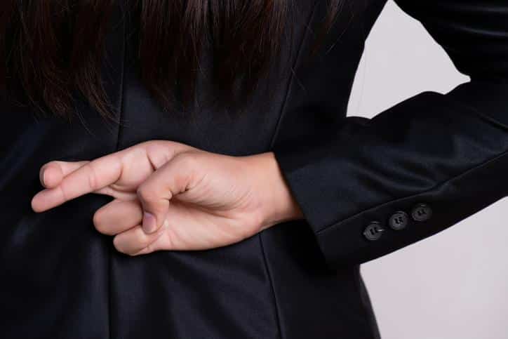 Close up businesswoman with her fingers crossed behind her back – concept for good luck or dishonesty business.