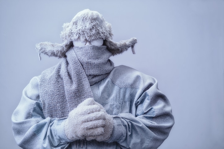 Man in parka, hat and scarf frozen from the cold