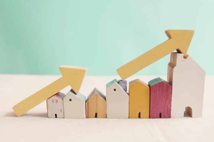 Wooden houses with yellow arrows up. housing boom, property market growing, high demand for real estate, house prices rising concept