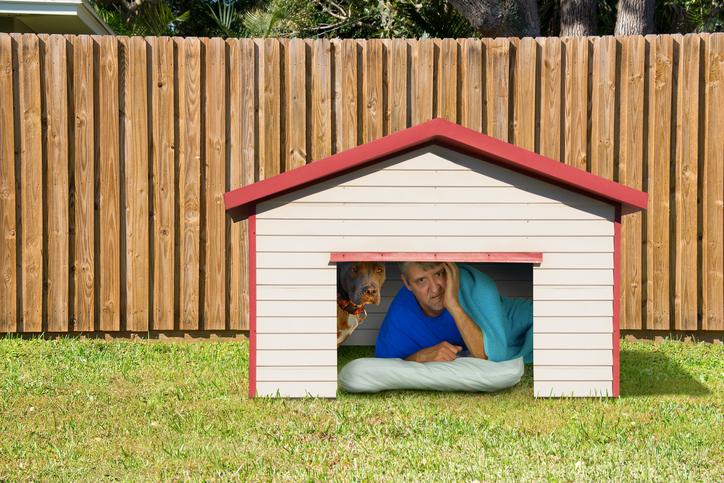 Husband or boyfriend man sleeping in the doghouse because of domestic problems