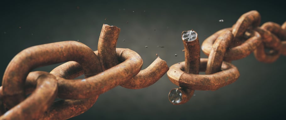 Rusty old chain broken in two with focus on the crumbling link, isolated on a dark defocused background. Wide horizontal composition.