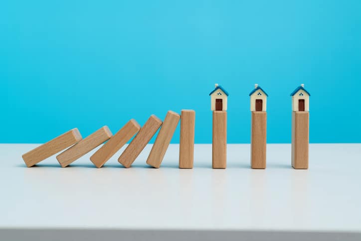 Wooden dominos falling to a model house