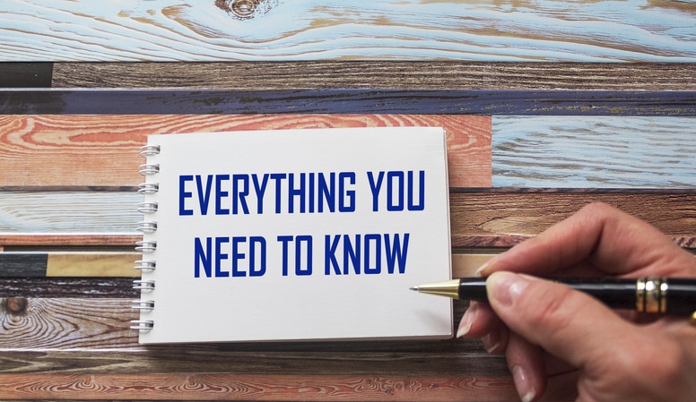 Everything you need to know. Motivational quote is written by a stiff hand on a notebook. Striped background.