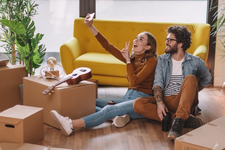 Happy millennial couple taking selfie in new home