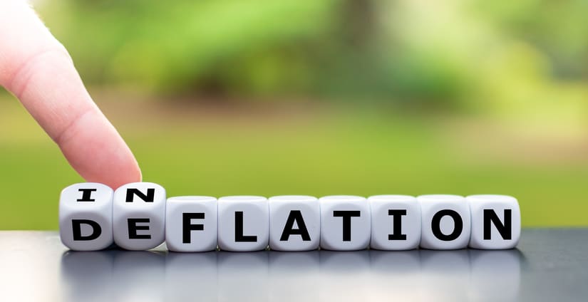 Hand turns a dice and changes the word “deflation” to “inflation”, or vice versa.