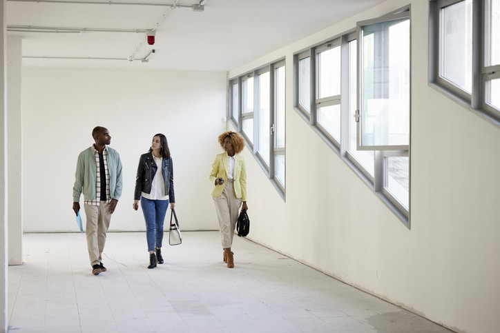 Real Estate Agent and Clients Touring Shell Condition Office Space