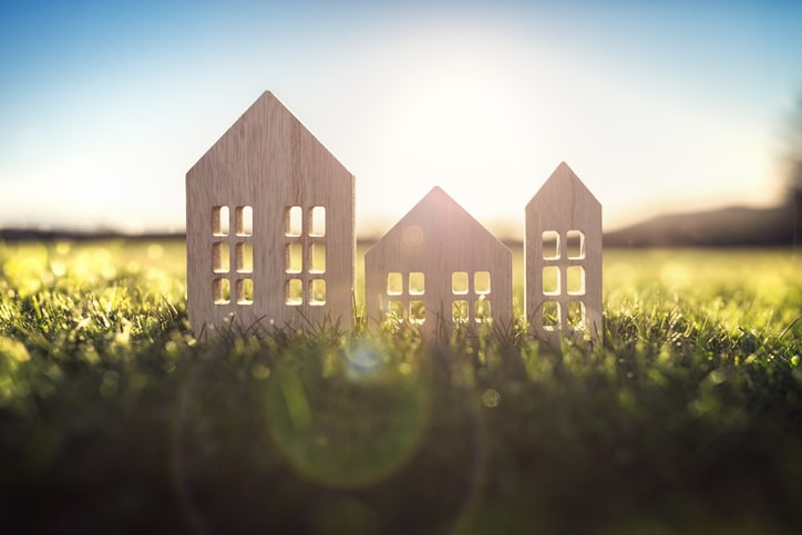 Ecological wood model house in empty field at sunset