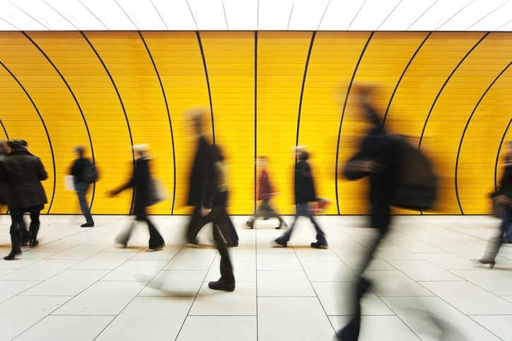 People blurry in motion in yellow tunnel down hallway