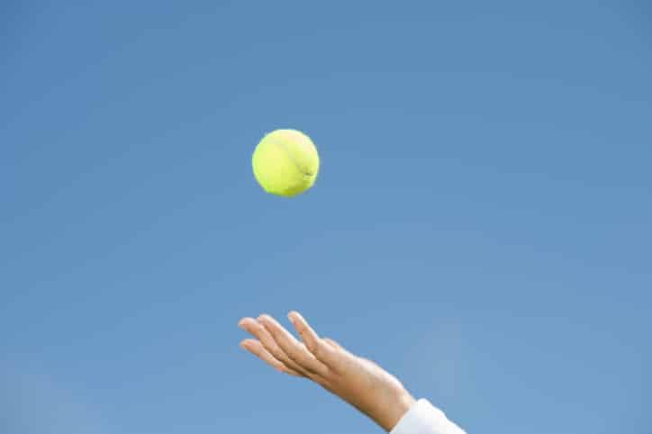 Hand throwing up a tennis ball