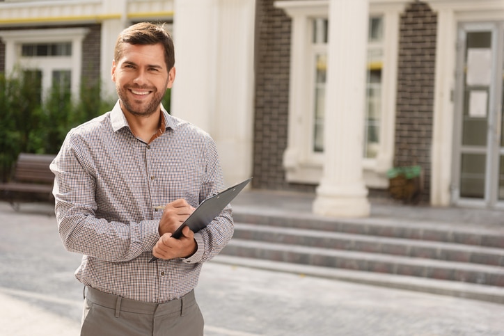 Smiling Real Estate Agent standing outside modern house