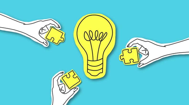 Hands with puzzle peaces around glowing light bulb
