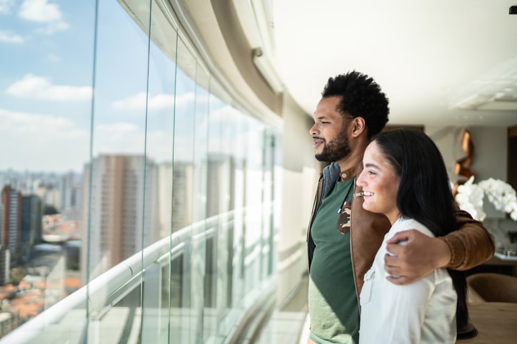 Side view of couple looking through the window of heir new apartment