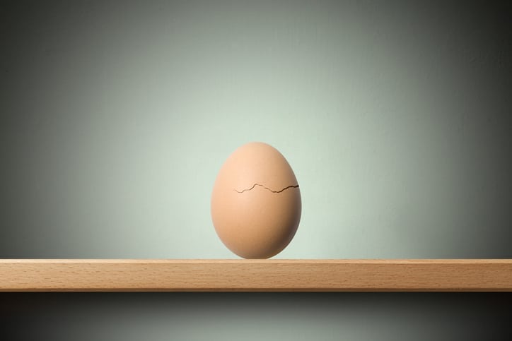Birth. An cracked egg on the shelf.