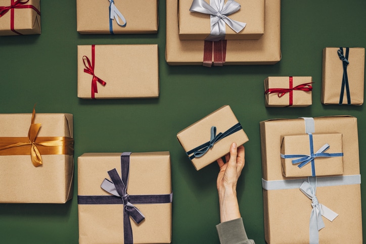 Anonymous Person Holding One of Many Gift Boxes on a Green Background