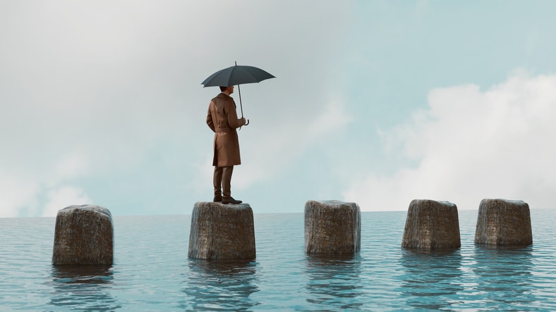 Man holds umbrella while standing on a rock in the sea Climate and Environment issues Housing Mortgage