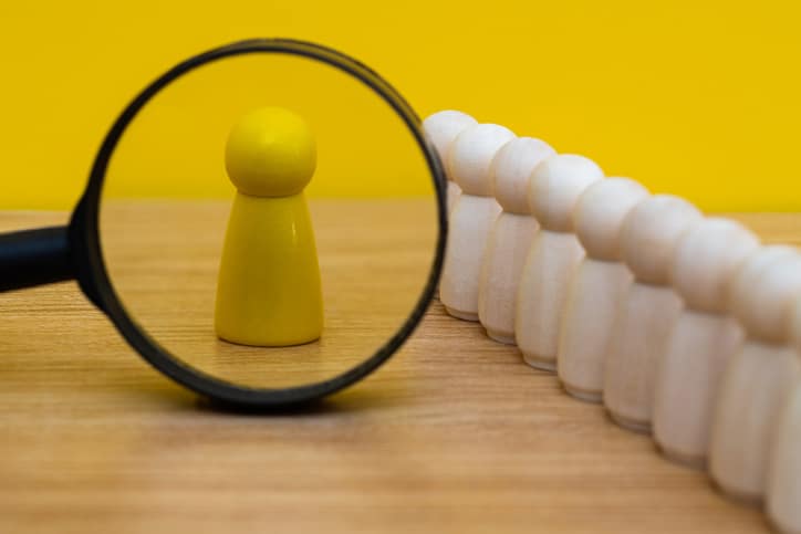 Magnifying glass looking at wooden figurine Real Estate Investigation