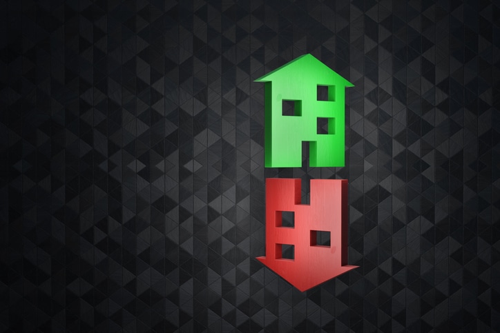 House shaped wooden boards representing a green up arrow and a red down arrow on dark background. Illustration of the concept of price fluctuation of houses and apartments Home Prices Decrease Increase Real Estate