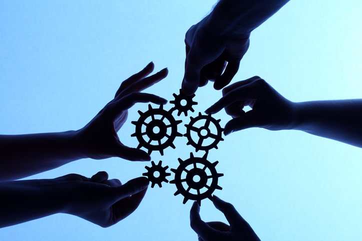 Silhouette of hands holding cogs and gears Real Estate Teamwork