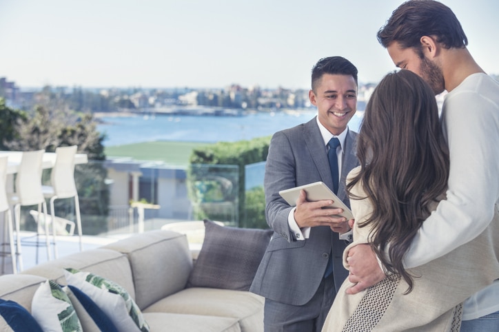 Real estate agent with couple in luxury home. Happy Clients Real Estate Agent