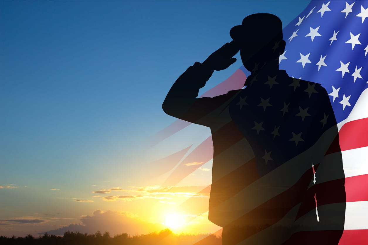 Silhouette of soldier with USA flag against the sunset